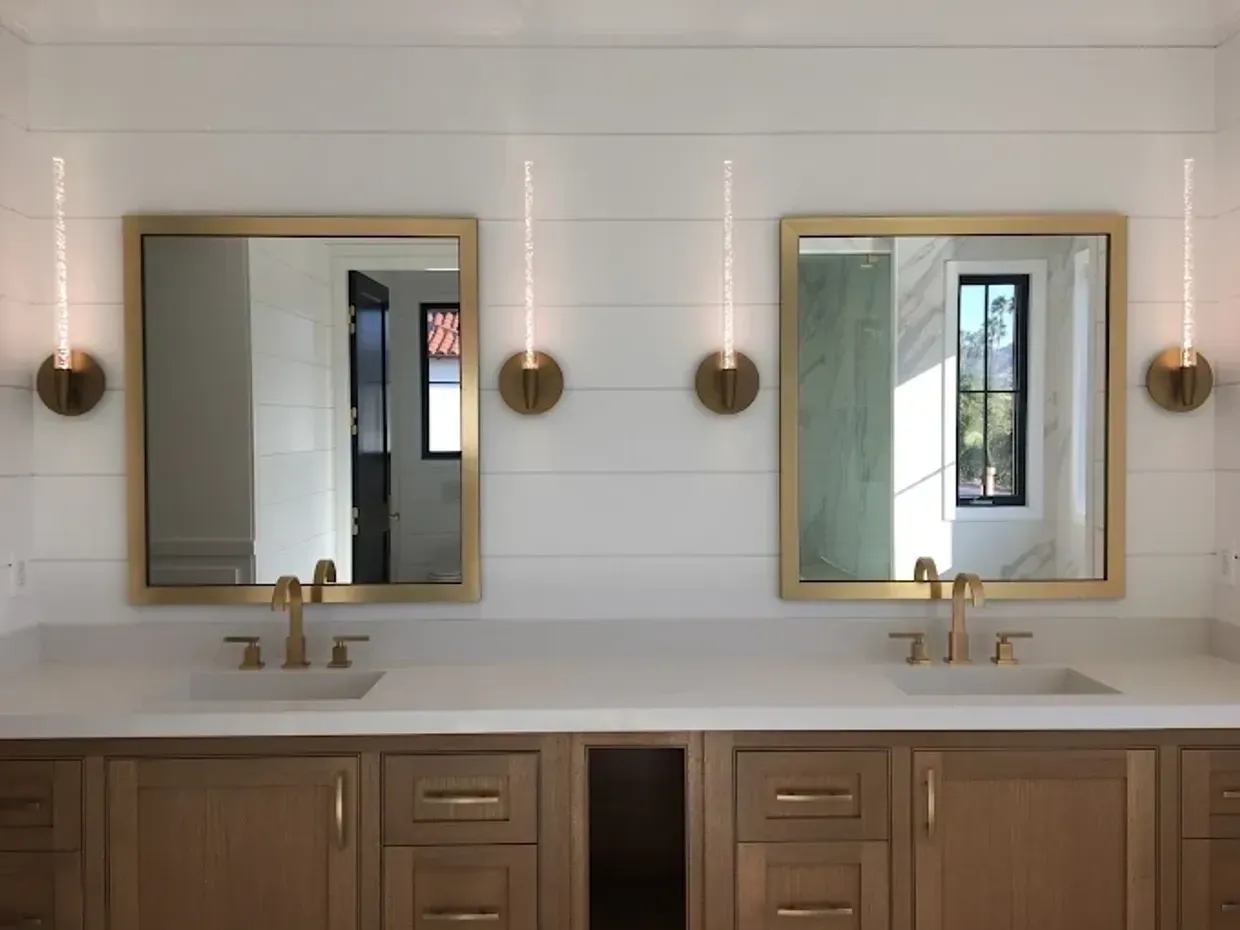 Remodeled Portland master bathroom with white-oak double vanity, brass-framed mirrors, brass sconces, shiplap wall, and quartz countertop